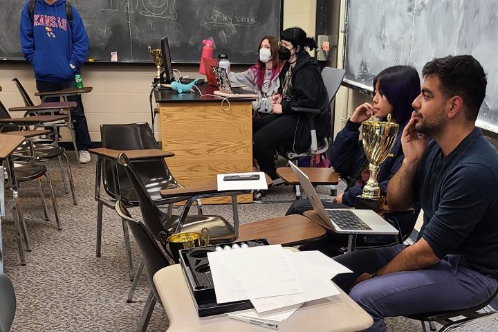 Policy students sit in a chair listening during a round